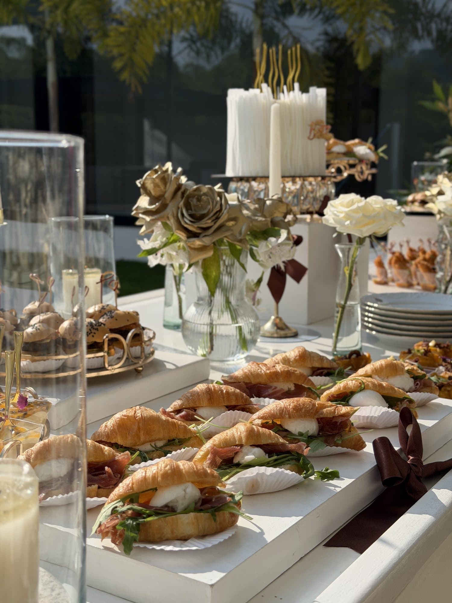 Croissants con jamón serrano en una mesa con flores doradas