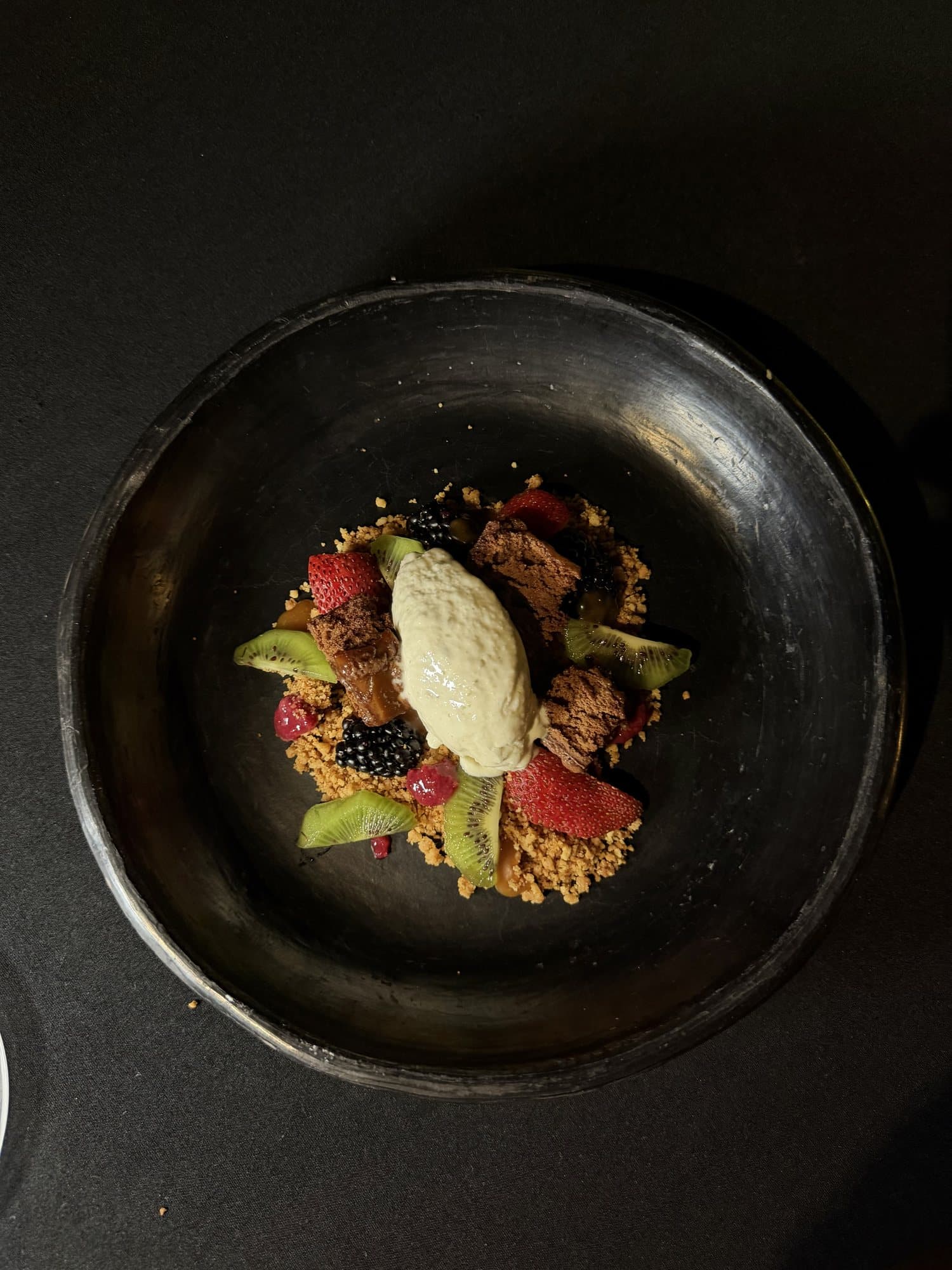 Postre con frutos rojos y kiwi en plato de barro